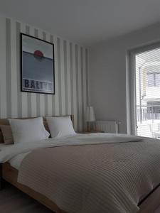 - une chambre blanche avec un grand lit et une fenêtre dans l'établissement Apartament Baltica - Rezydencja Ustronie Morskie, à Ustronie Morskie