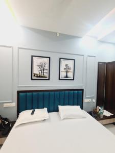 een bed in een kamer met twee foto's aan de muur bij Hotel Kaanjee in Sīkar