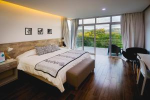 um quarto com uma cama e uma grande janela em La Posada Del Qenti em Villa Carlos Paz