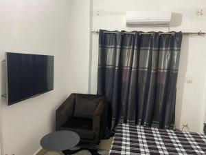 a living room with a television and a chair at Appartement Studio Damou in Bamako