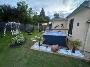 a backyard with a hot tub in the grass at La Maison des Plaisirs Love room in Champigny-sur-Yonne