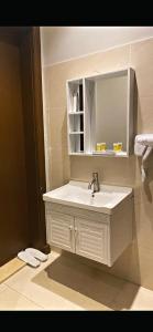 La salle de bains est pourvue d'un lavabo blanc et d'un miroir. dans l'établissement أضواء الشرق للشقق الفندقية Adwaa Al Sharq Hotel Apartments, à Sīdī Ḩamzah