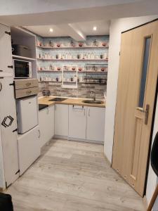 kuchnia z białymi szafkami i drewnianymi drzwiami w obiekcie Przylesie Dom Turystyczny w Ostródzie