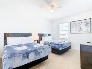 een slaapkamer met twee bedden en een plafondventilator bij Experience Villa 12-Bed Vacation Haven BV368 in Kissimmee +84 foto's