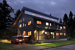 a van parked in front of a house at night at Bears Den Mountain Lodge in Hakuba