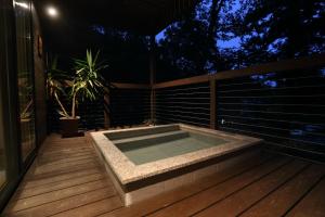 a hot tub sitting on a deck at night at Bears Den Mountain Lodge in Hakuba