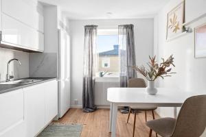 eine weiße Küche mit einem Tisch und einem Fenster in der Unterkunft Bambinas Guest House Hässleholm in Hässleholm