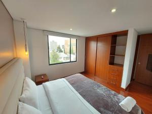 Un dormitorio con una cama grande y una ventana en Suites and Apartments Bogotá, en Bogotá