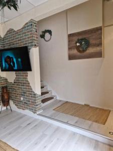 een woonkamer met een tv aan een bakstenen muur bij La Fontaine in Hauteville-Lompnes