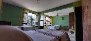 Habitación hospitalaria con 3 camas y paredes verdes en Casa Cejota en Huautla de Jiménez
