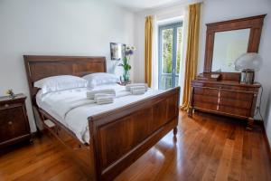 a bedroom with a large wooden bed and a dresser at Villa Laura in Gardone Riviera