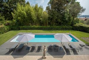 a swimming pool with two umbrellas and lounge chairs at Villa Laura in Gardone Riviera