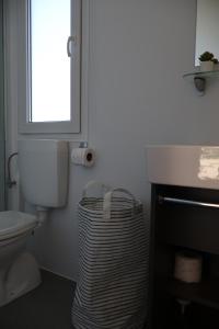 a bathroom with a toilet and a window and a trash can at Mobilna kućica Nika in Šimuni