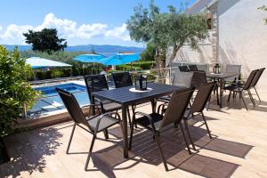 a patio with tables and chairs next to a pool at Apartments Šemper - HEATED POOL in Bol
