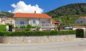 a house on a hill with a stone wall at Apartments Šemper - HEATED POOL in Bol