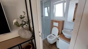 a bathroom with a toilet and a vase with flowers in it at Mobile home 249 - Large Terrace & Private Jacuzzi in Selce