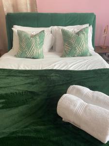 uma cama verde e branca com almofadas em The Lily Pad em Corfe Mullen