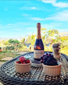 eine Flasche Wein und Obstschalen auf dem Tisch in der Unterkunft Rancho da Montanha Cipó in Serra do Cipo