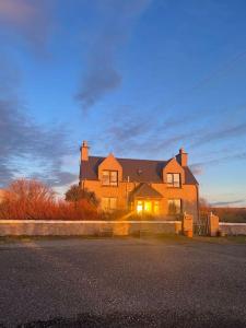 una grande casa seduta sul lato di una strada di Isle-of-Lewis delightful cosy croft house retreat a Barvas