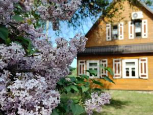een boom met paarse bloemen voor een huis bij Dębowe Królestwo Leśniczówka w Puszczy na wyłączność in Policzna