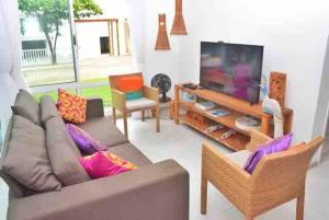 ein Wohnzimmer mit einem Sofa und einem Flachbild-TV in der Unterkunft Toquinho · Casa de Luxo c/ piscina em cond fechado - Toquinho in Ipojuca