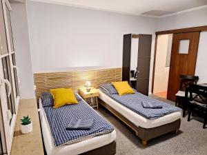 2 łóżka w pokoju z żółtymi poduszkami w obiekcie Dom na Folwarku POKOJE I APARTAMENTY, BEZPŁATNY ZAMYKANY PARKING NA TERENIE POSESJI w Kielcach
