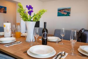 een tafel met een fles wijn en een vaas met bloemen bij Apartments Lucija Mari in Tribunj