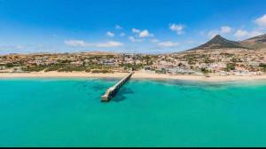 a view of a beach with a pier in the water at SandyBeachApartment in Porto Santo