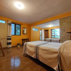 a bedroom with two beds and two windows at Casa Cejota in Huautla de Jiménez