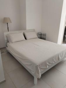 uma cama com lençóis brancos e almofadas num quarto em Appartamento Suite Antiche Terme - Zero Barriere em Acqui Terme
