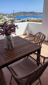 una mesa de madera con sillas y un jarrón de flores en el balcón en Plakourakia, en Finikas