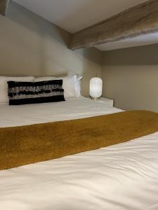 ein Schlafzimmer mit einem Bett mit weißer Bettwäsche und einer Lampe in der Unterkunft Appartements St. Pancrace in Corte