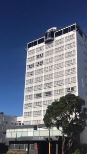 un edificio blanco alto con un árbol delante de él en Bay Plaza Hotel, en Wellington