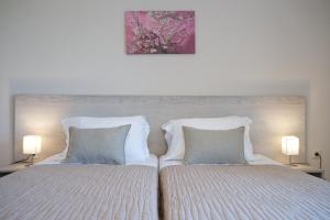 Jasmine Maisonette في Razáta: سرير مع وسادتين ولوحة فوقه