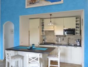 a kitchen with white cabinets and a blue wall at Holiday House La Rosa dei Venti in Palau