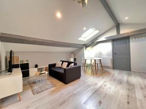 LE CLOS CHASSAING N5-WiFI-CENTRE VILLE-CLIMATISATION في بيريجو: غرفة معيشة مع أريكة سوداء وطاولة