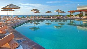 a swimming pool with chairs and umbrellas and the ocean at Beach Front Place in Cancún