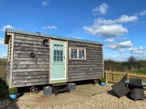 a tiny house with a green door and a table at Luxury Shepherd Hut in Kelham