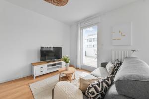 een woonkamer met een grijze bank en een tv bij Appartement Chic au Coeur de Massy in Massy