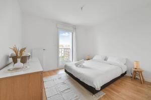 een witte slaapkamer met een bed en een raam bij Appartement Chic au Coeur de Massy in Massy