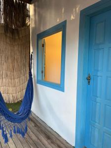 a room with a blue door and a hammock at Pousada Crocodilo Caraíva in Caraíva