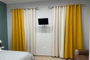 a bedroom with two yellow curtains and a television at Miambra 