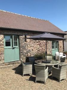 a patio with a table and chairs and an umbrella at The Barn at Kingston, Beautiful converted barn in tranquil countryside in Pembroke