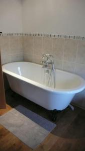 a white bath tub with a faucet in a bathroom at The Barn at Kingston, Beautiful converted barn in tranquil countryside in Pembroke