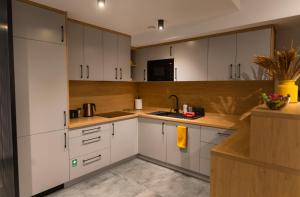 a kitchen with white cabinets and a sink at Apartamenty Loftove in Wadowice