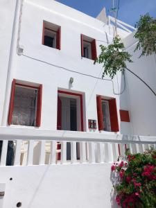 a white building with red windows and flowers at Alex oldtown sea view rooms and appartments in Mýkonos City