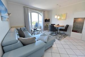 ein Wohnzimmer mit einer blauen Couch und einem Tisch in der Unterkunft "Appartementhaus Deichgraf" Appartement D445 in Döse