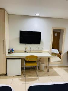 Habitación con escritorio y TV en la pared. en Hotel Maione, en Goiânia