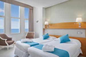 Habitación de hotel con 2 camas y almohadas azules en Hotel & Talasoterapia Zelai - HSS00653 en Zumaia