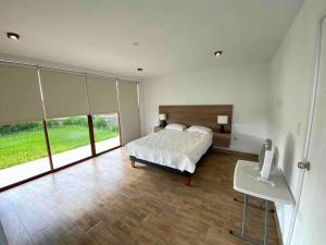 a bedroom with a bed and a desk and windows at Camelia Chincha® Hermosa Casa de Playa y Campo in San Pablo